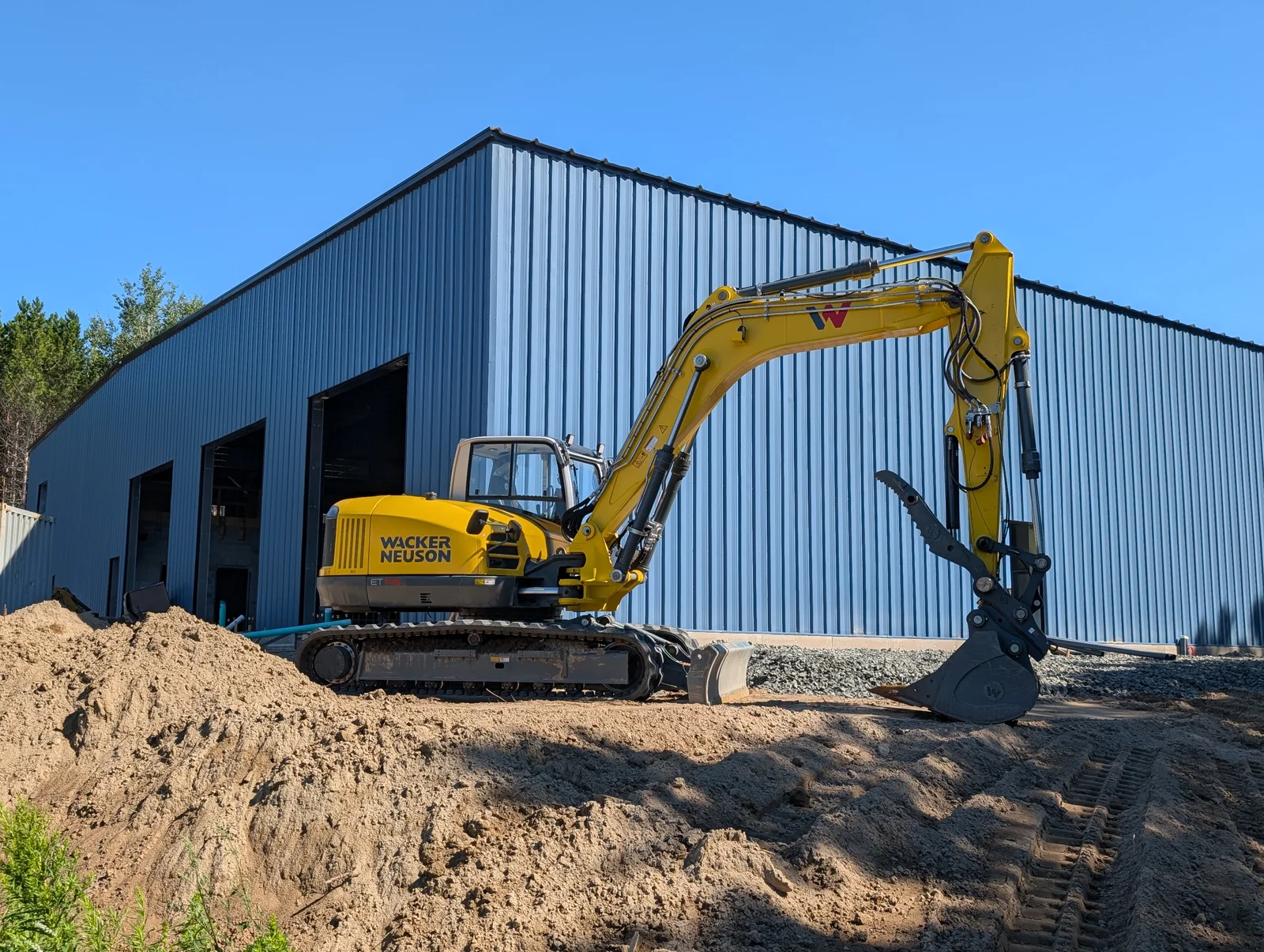 Wacker Neuson excavator working outside a construction building